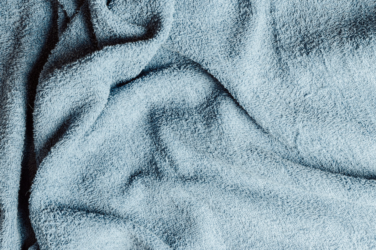Used grey face cloth with makeup residue, resting beside a bathroom sink